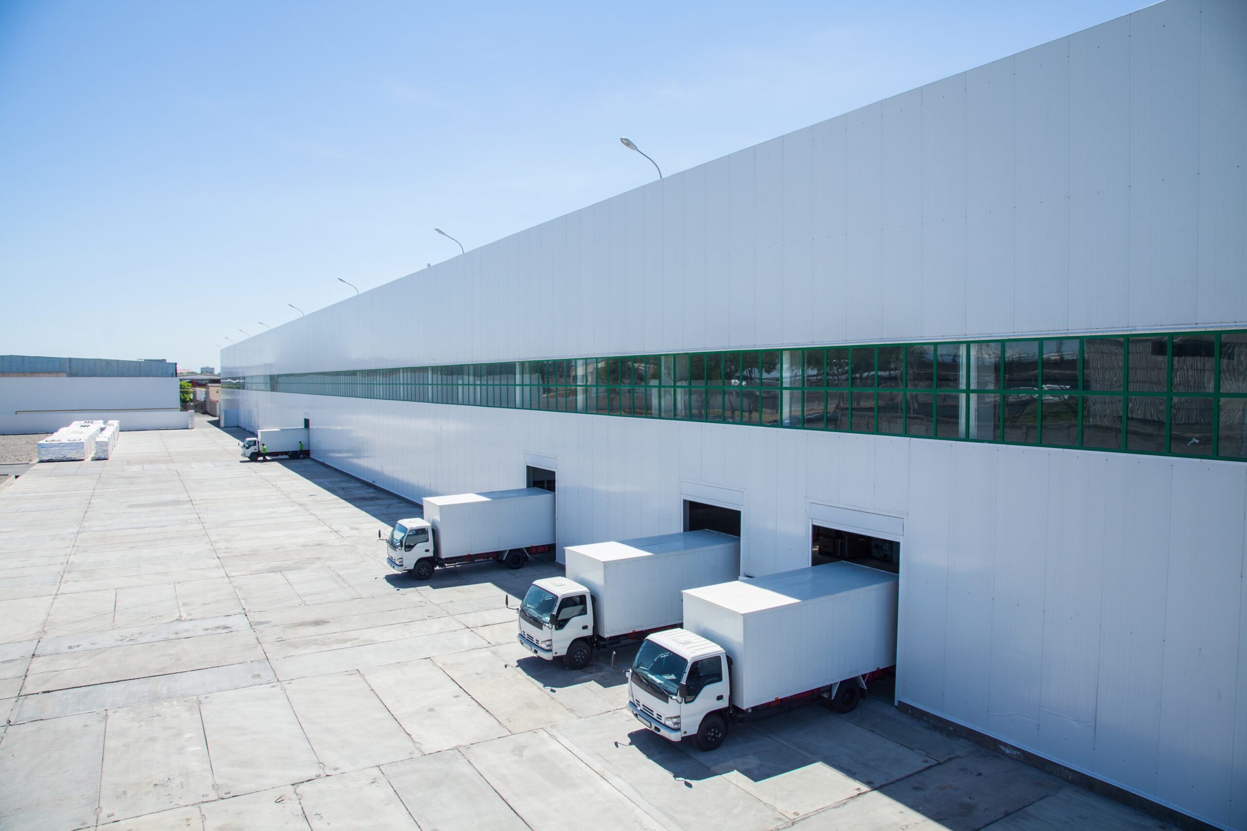 Image of outside a warehouse with a line of warehouse trucks backed into bays