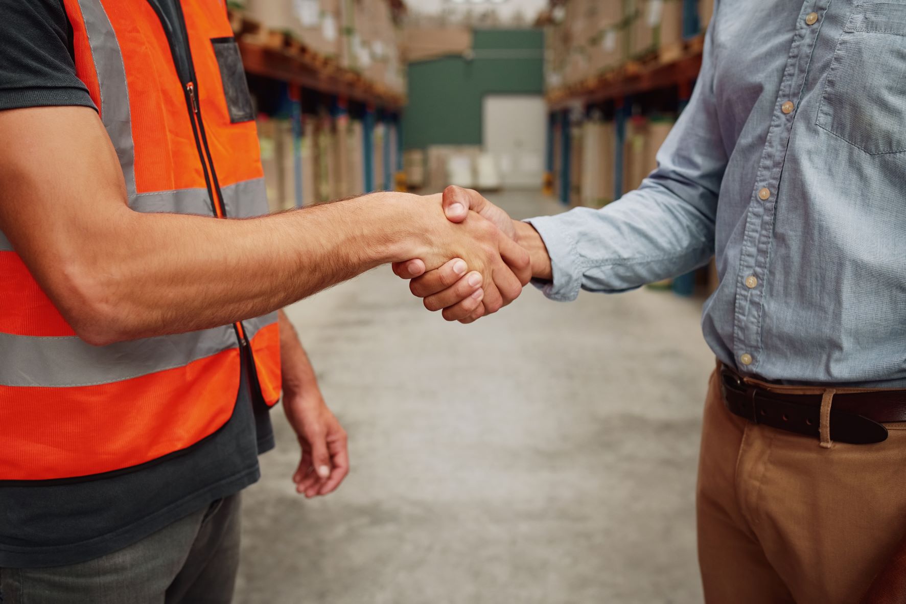 Two people shaking hands in a warehouse